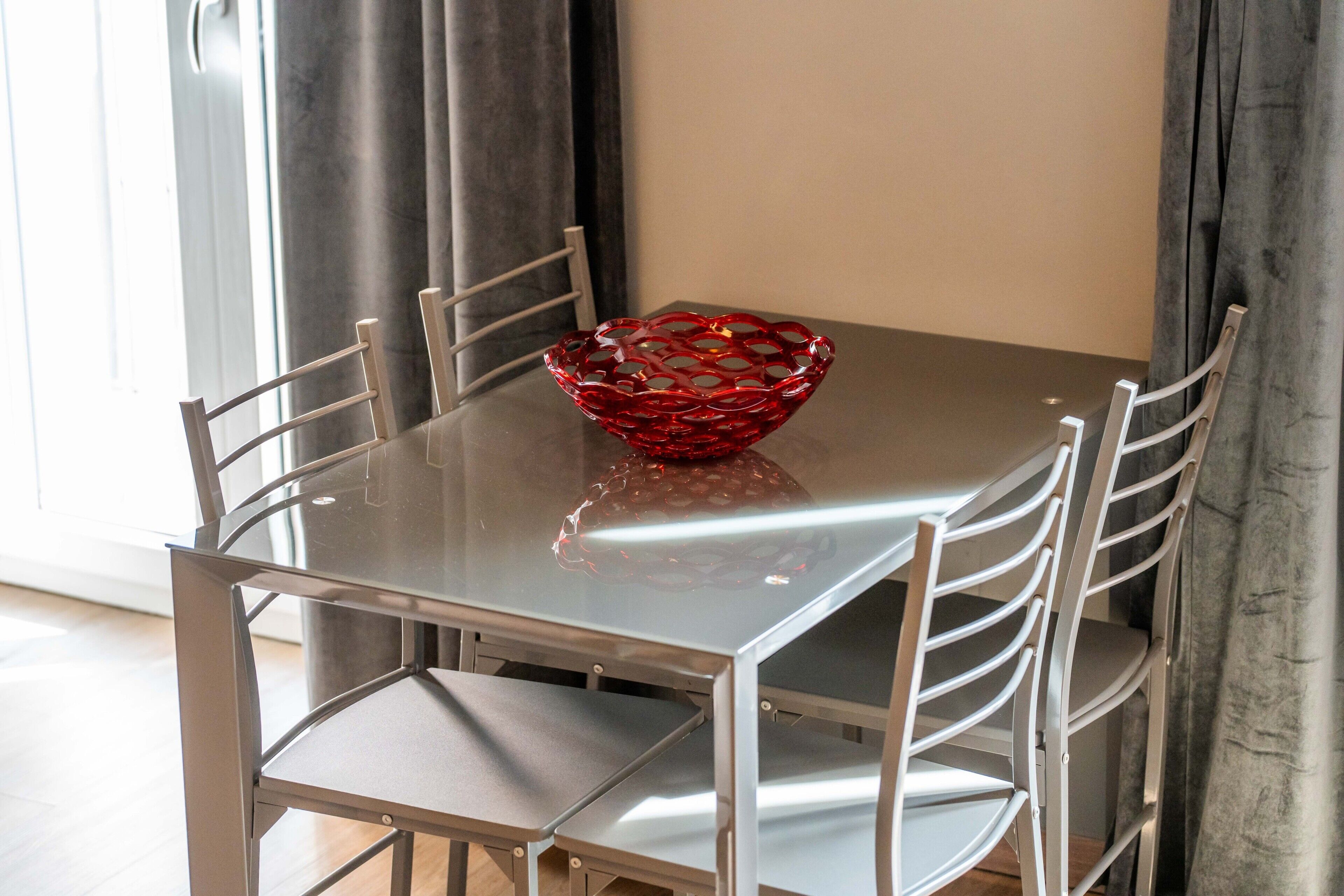 A dining table with a red glass bowl, surrounded by metal chairs.