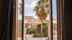 Un balcón con vista a un paisaje urbano, que incluye edificios y palmeras.
