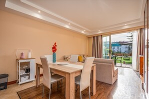 Uma sala de jantar com mesa de madeira, cadeiras e um carrinho pequeno com utensílios de cozinha.