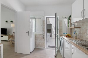 A modern kitchen with a washing machine, a sink, and a dining area with a table and chairs. - Apartment 'Refúgio Estrela Do Mar' with Private Terrace, Wi-Fi and Air Conditioning (Quarteira)