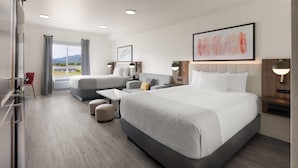 A modern hotel room with a large bed, a sofa, a desk, and a view of the outdoors. - Hawthorn Extended Stay by Wyndham Jackson Alpine (Alpine)