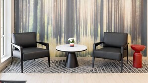 A room with two black leather chairs, a round table with a white top, and a small red stool. - Hawthorn Extended Stay by Wyndham Jackson Alpine (Alpine)