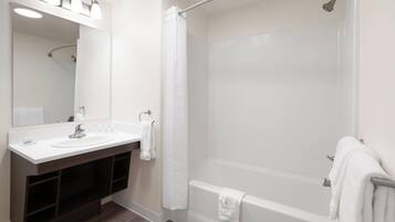 Un baño moderno con tocador doble, un espejo grande, ducha con puerta de vidrio curvada y bañera.