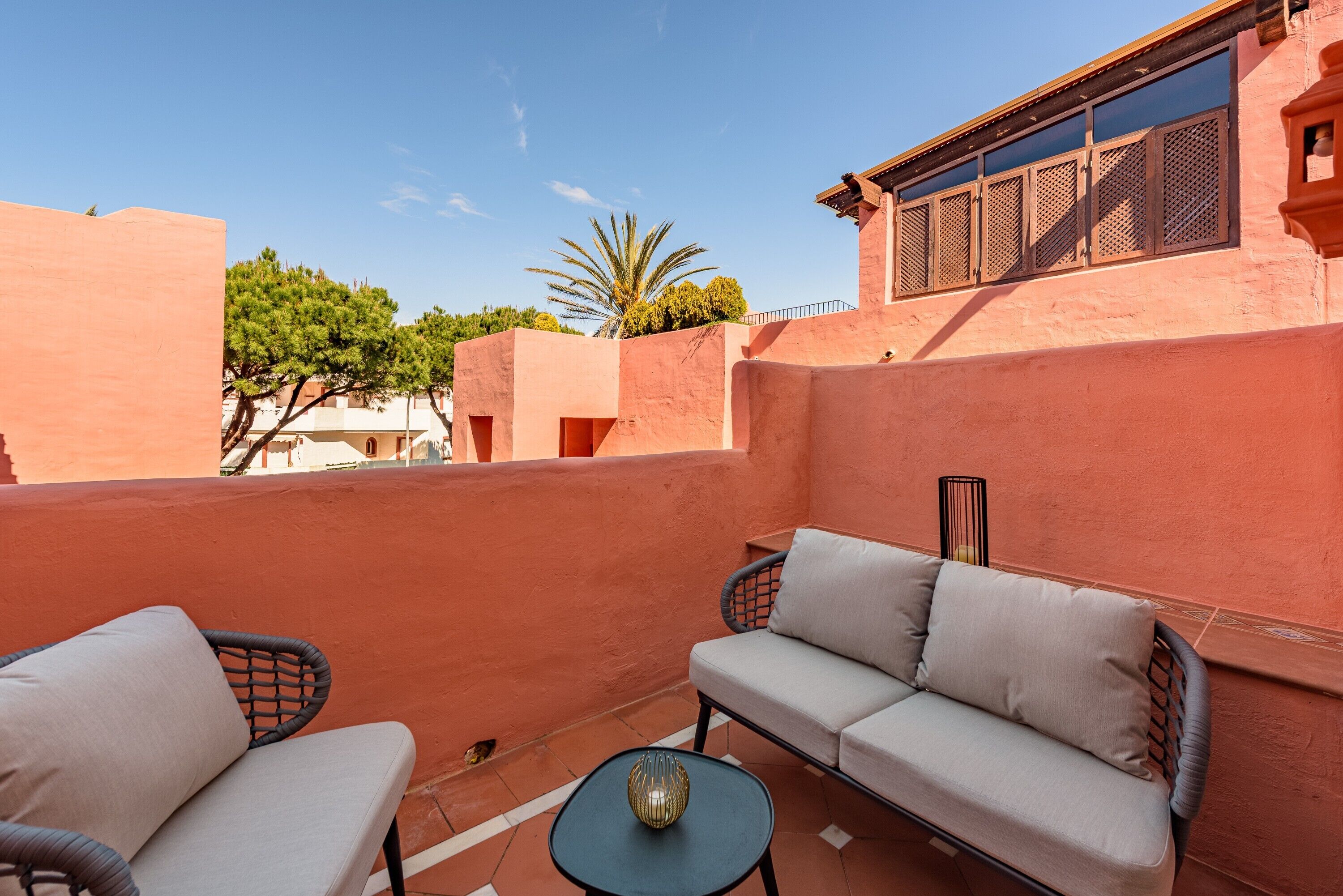 An outdoor seating area with a sofa and chairs, a small table, and a decorative vase.