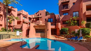A swimming pool with a curved edge, surrounded by a red-tiled deck.