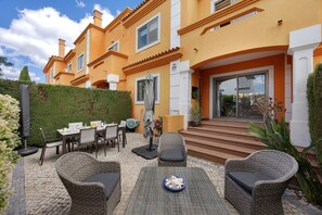 A patio with wicker furniture, a dining table, and a blue plate of mushrooms.