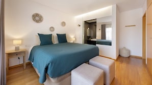 A bedroom with a bed, bedside tables, a mirror, and a small round seating area. - Villa 'Casa Giorianna - Luxury' with Shared Pool, Wi-Fi and Air Conditioning (Luz de Tavira)