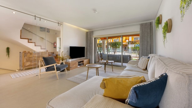 A modern living room with a sofa, TV, and a staircase. - Villa 'Casa Giorianna - Luxury' with Shared Pool, Wi-Fi and Air Conditioning (Luz de Tavira)