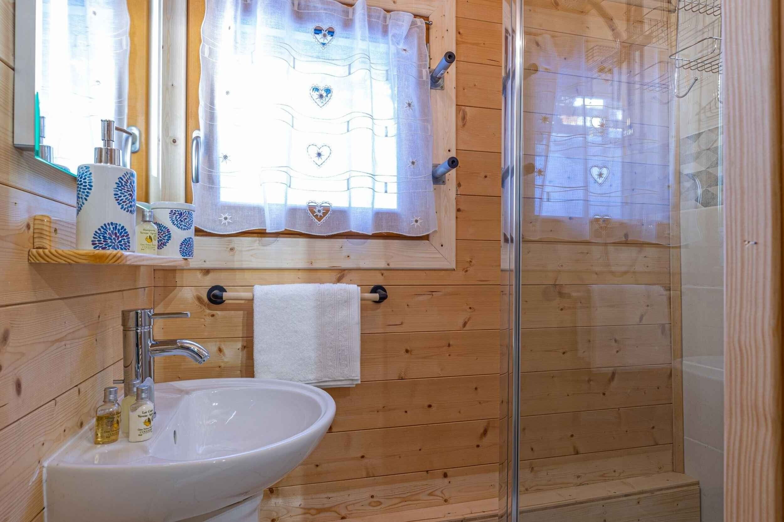 A wooden cabin bathroom with a sink, mirror, and shower.
