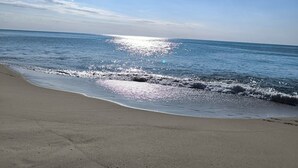 Une plage avec un ciel dégagé et la lumière du soleil se reflétant sur l’eau.