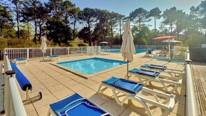A pool area with lounge chairs and umbrellas. - Cozy apartment between lake and ocean – Terrace & shared pool in Carcans-Maubuisson (Carcans)