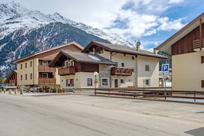Un edificio con fachada de madera, un cartel de estacionamiento y montañas nevadas al fondo.