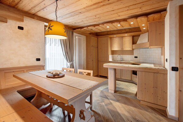 Un interior de madera con una mesa de comedor, sillas, una lámpara colgante y una zona de cocina.