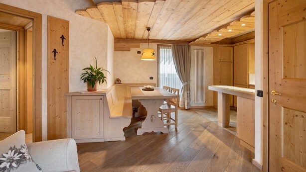 A wooden interior with a dining area, kitchen, and a door.