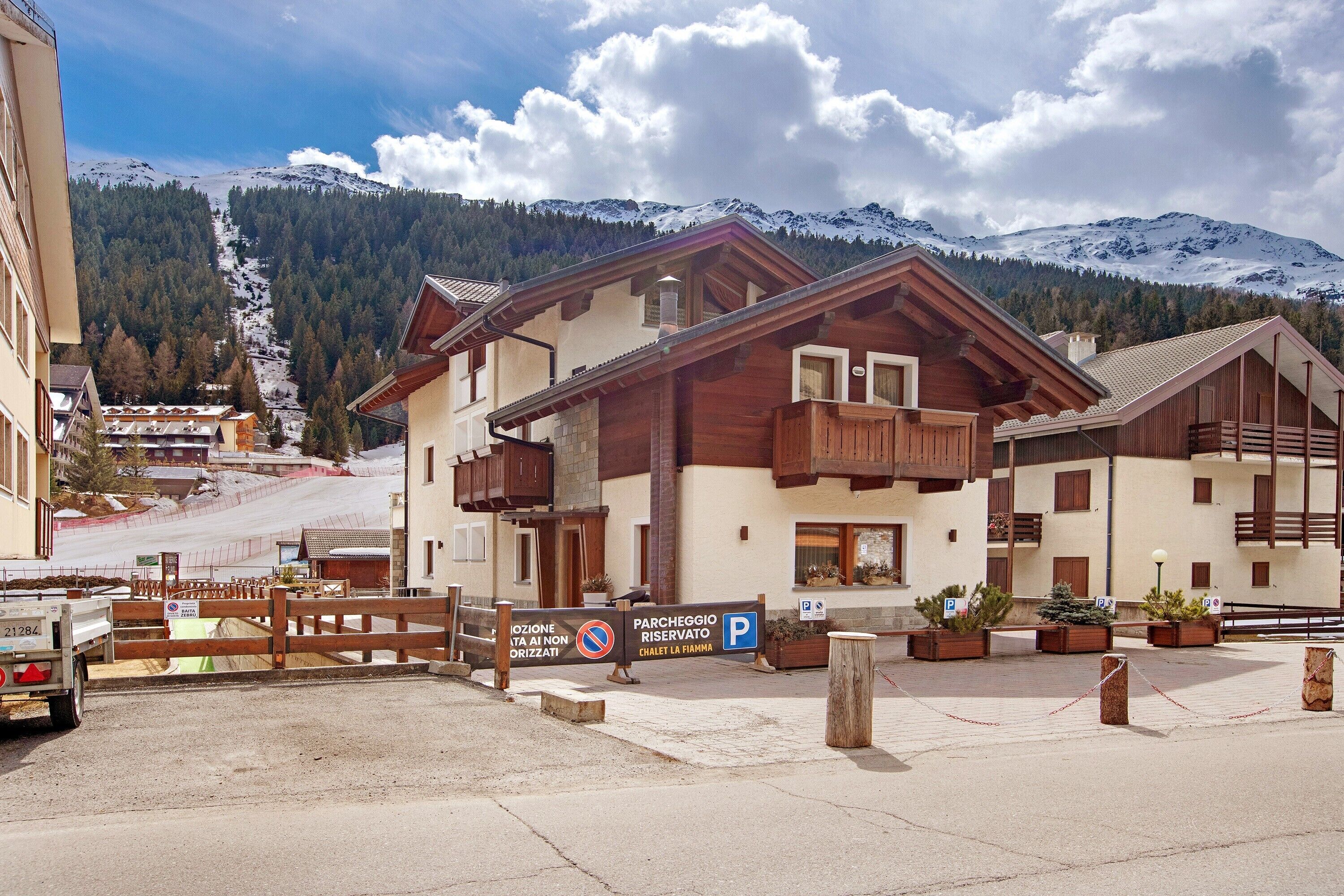 Ein Hotel mit Holzfassade, Balkonen und Blick auf schneebedeckte Berge.