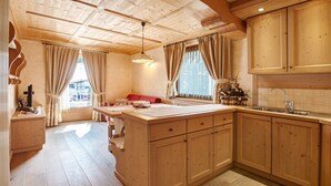 A wooden interior with a kitchen area, a dining table, and a sofa. - Apartment 'Genziana' with Mountain View, Private Terrace and Wi-Fi (Santa Caterina)