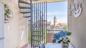 Un balcón con una escalera de caracol, una mesa con un centro de mesa floral y un adorno montado en la pared.