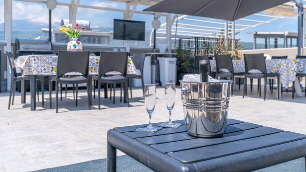 Un área de comedor al aire libre con mesas, sillas y una sombrilla grande.