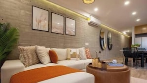 Een moderne woonkamer met een bank, poef en een eethoek met tafel en stoelen.