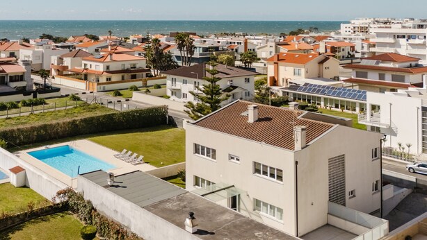 Un barrio residencial con casas modernas, una piscina y vista al mar.