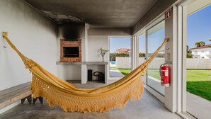 Una hamaca en una habitación con chimenea de ladrillo, un banco y un extintor.