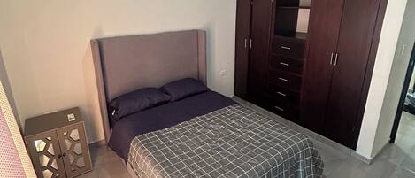Un dormitorio con cama, armario y aire acondicionado.