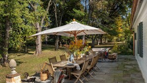Een terras met een eettafel, stoelen, een parasol en een mand.