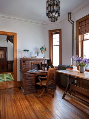 Une salle d’étude équipée d’un bureau en bois, de deux chaises, d’un radiateur et d’une fenêtre donnant sur un paysage agréable.