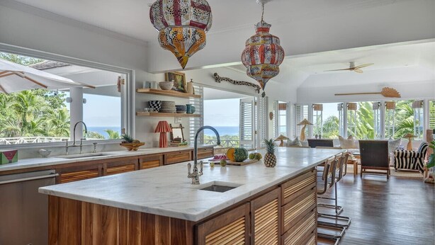 Una cucina moderna con un'ampia isola, mobili in legno e vista sull'oceano.