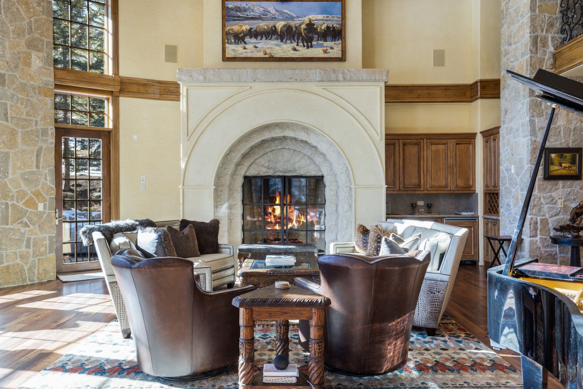 A spacious living room with a fireplace, leather furniture, and a stone wall.
