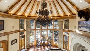 Una habitación amplia con techo alto, ventanas grandes, chimenea y candelabro.