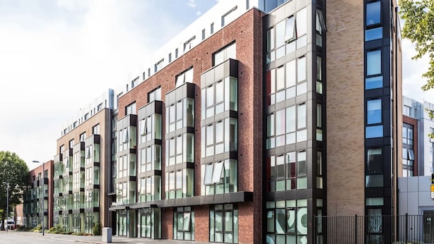 A modern building with multiple floors, large windows, and a mix of brick and glass facades. - Student Only Arbury Court in Kingston (New Malden)
