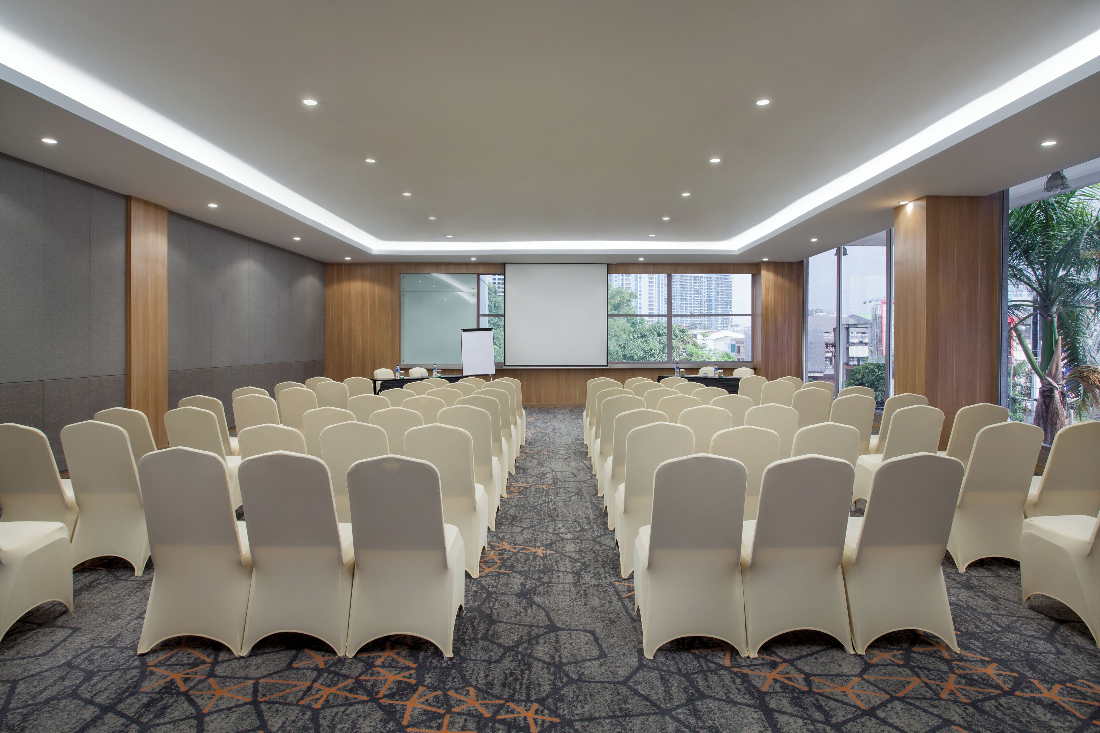 A conference room with rows of chairs, a podium, and a large window with a city view.