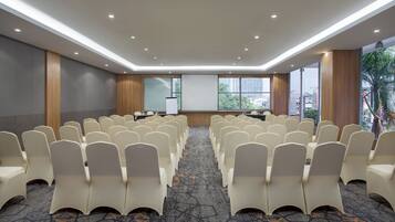 A conference room with rows of chairs, a podium, and a large window with a city view.