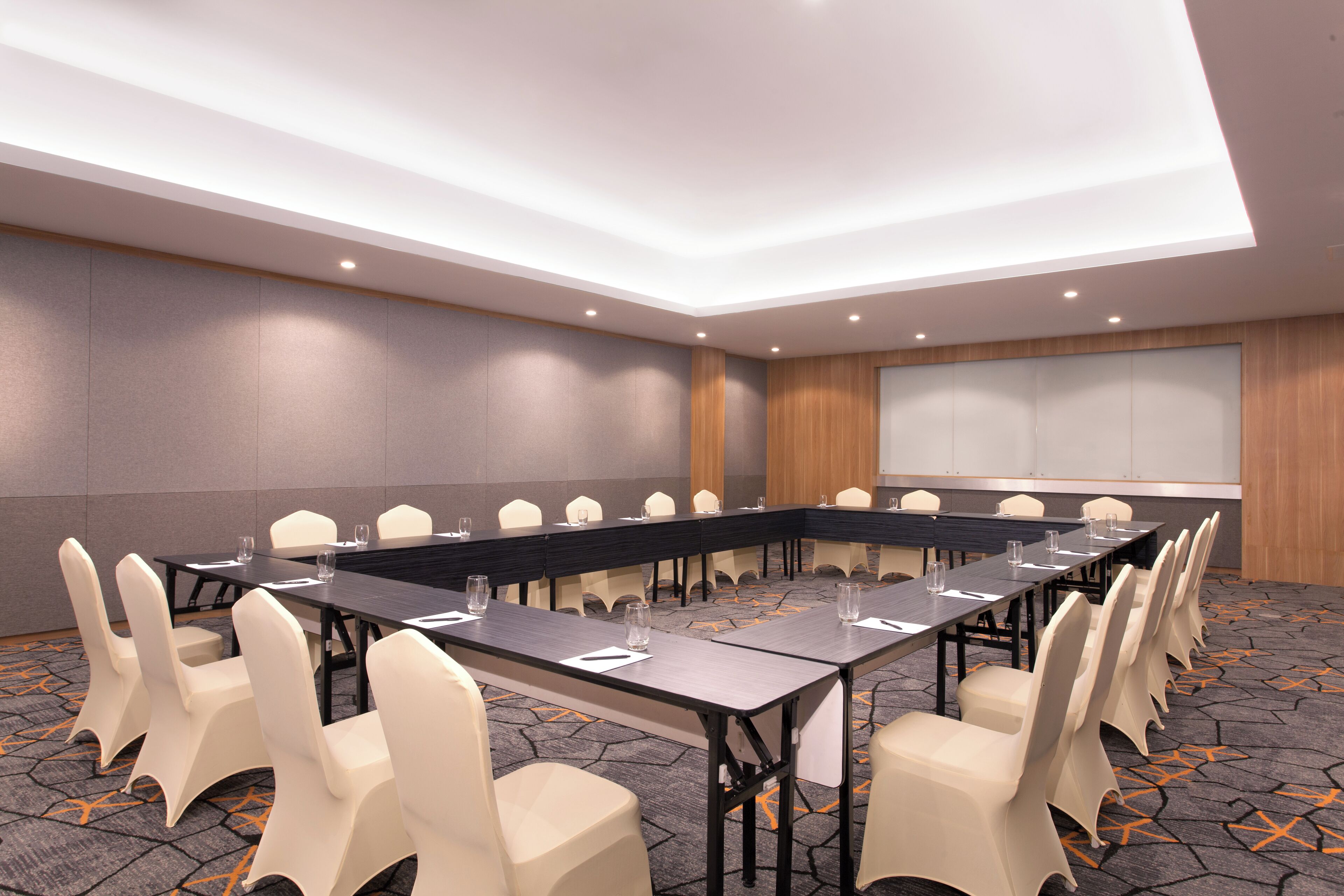 A conference room with a long table, multiple chairs, and a projector screen.