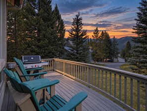 Terraza con mobiliario exterior y una parrilla, con vistas a un paisaje montañoso.