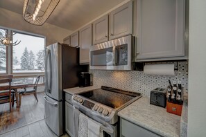A modern kitchen with stainless steel appliances, a built-in microwave, and a toaster. - Cozy Rustic Condo minutes from Big Sky Resort & Town Center! Hot Tub & Sauna! (Big Sky)
