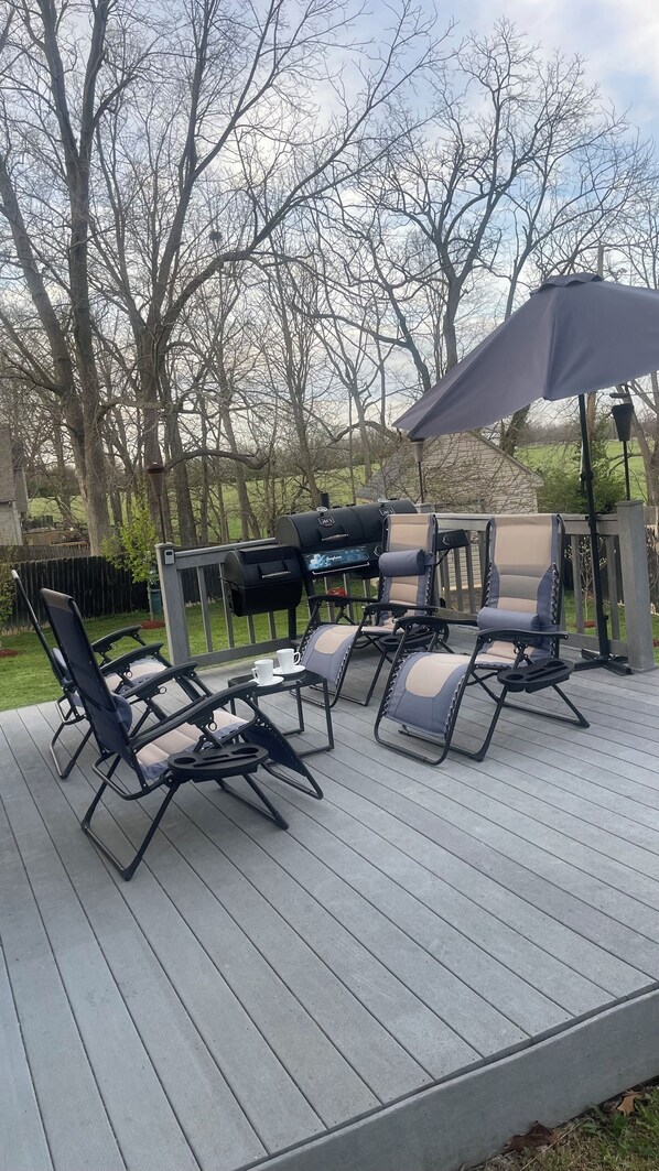 An outdoor deck with a grill, lounge chairs, and a table.