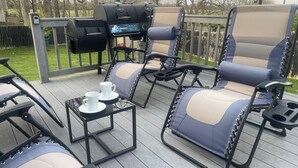 Een terras met buitenmeubilair, een barbecue en een tafel met bekers.