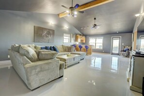 A spacious living room with a grey sofa, a coffee table, and a ceiling fan.