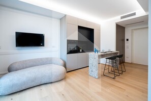 Una cocina moderna con televisión de pantalla plana, horno integrado y encimera de mármol.