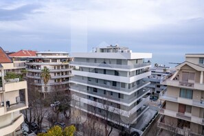 Un edificio residencial de varios pisos con balcones, un estacionamiento y vista al mar.