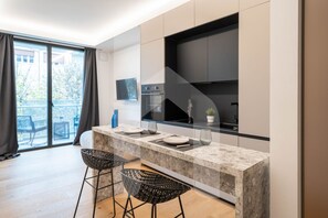 Una cocina moderna con encimera de mármol, dos taburetes negros y un horno empotrado.