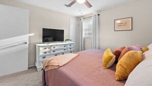 A bedroom with a bed, dresser, TV, ceiling fan, and a framed quote on the wall. - 4 bedroom, King Bed, 4 min to Fairgrounds, TVs in all Rooms (Perry)