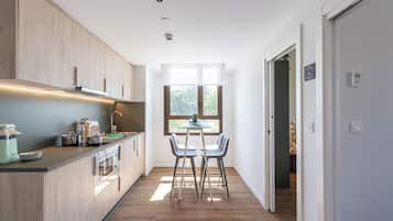 A modern kitchen with wooden cabinets, a built-in oven, and a dining area with two chairs and a table.