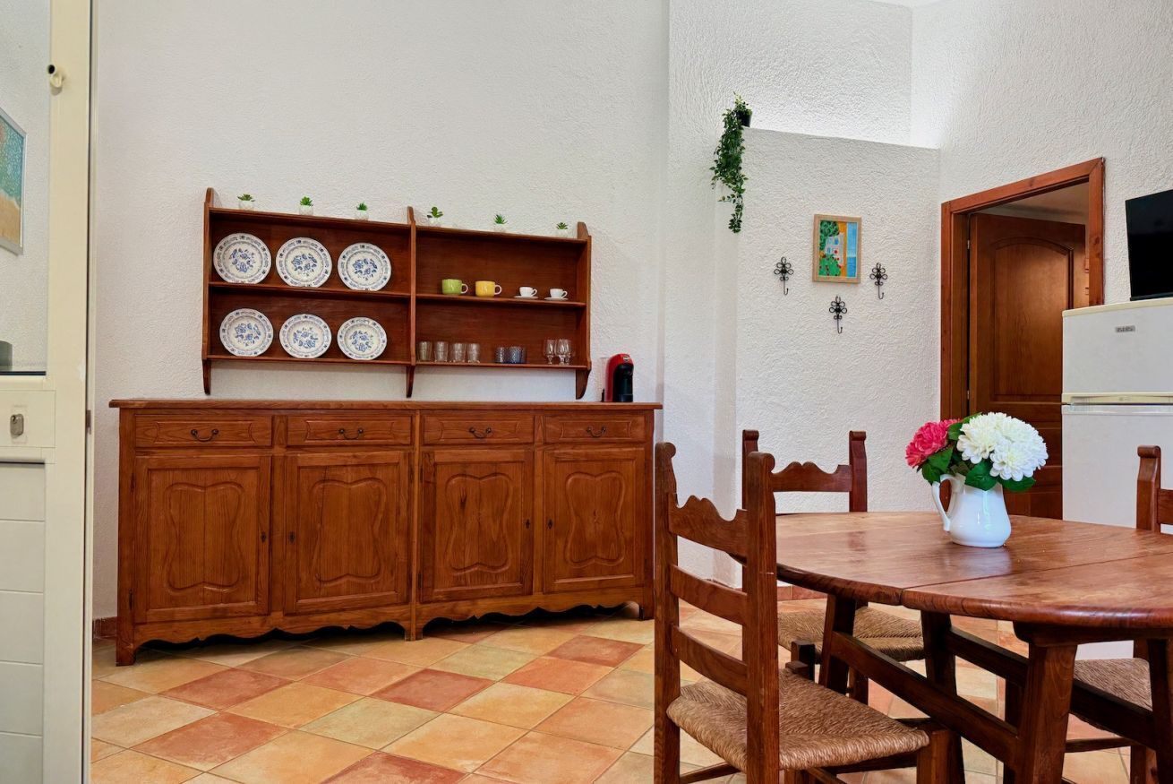 Un coin repas avec une table et des chaises en bois, un buffet orné d’assiettes décoratives et une petite plante accrochée au mur.