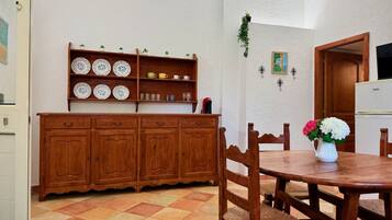 Un coin repas avec une table et des chaises en bois, un buffet orné d’assiettes décoratives et une petite plante accrochée au mur.
