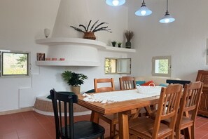 Een eetgedeelte met een houten tafel, stoelen en een wit plafond.