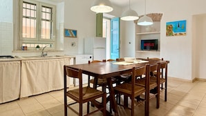 A kitchen with a dining table and chairs, a refrigerator, and a window with a view. - [Leccio] Comfort and Nature in Orosei (Orosei)