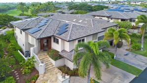 Ein Wohngebäude mit Solaranlage auf dem Dach, einem gepflegten Garten und Blick auf einen Golfplatz.